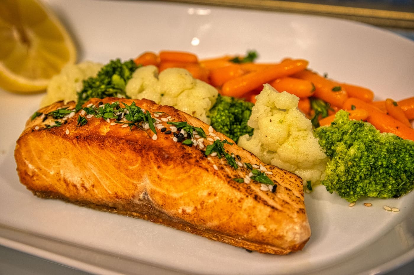 Grilled salmon fillet served with carrots, cauliflower and broccoli on a plate